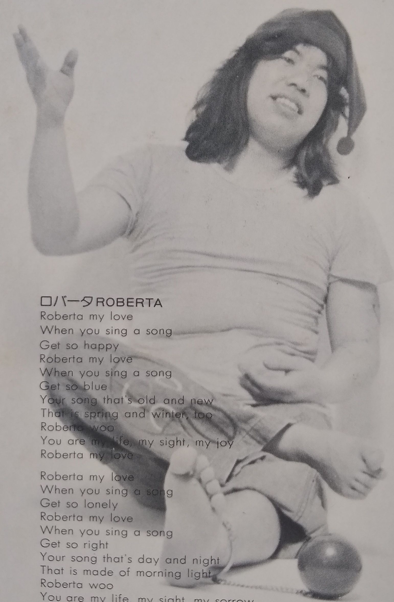 A picture of Hiro Tsunoda from the back cover. He is barefoot and wearing a pointed hat. The lyrics to his song "Roberta" partially cover the image.