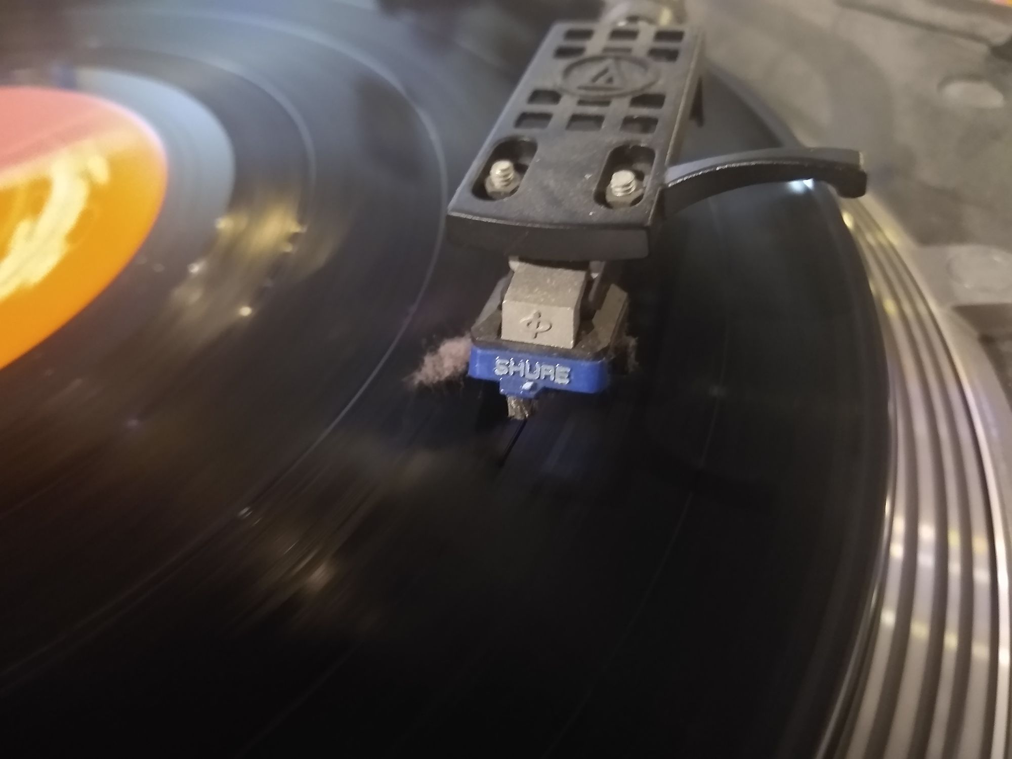 Picture of a vinyl record being played, with a seriously large amount of dust under the cartridge